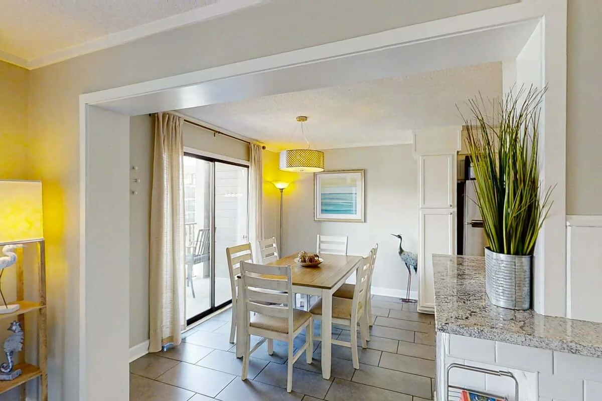 A dining area with a table and chairs beside large sliding glass doors.