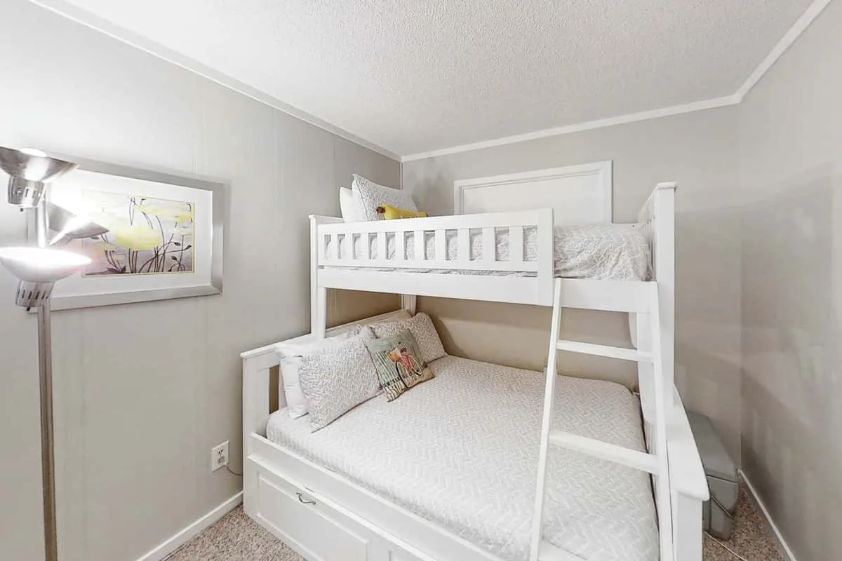 Un dormitorio con una litera blanca y una obra enmarcada en la pared.