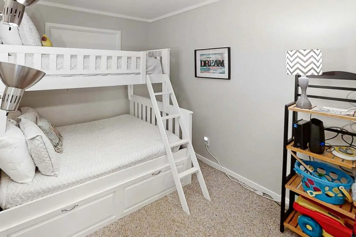 Un dormitorio con una litera blanca y una pequeña estantería.