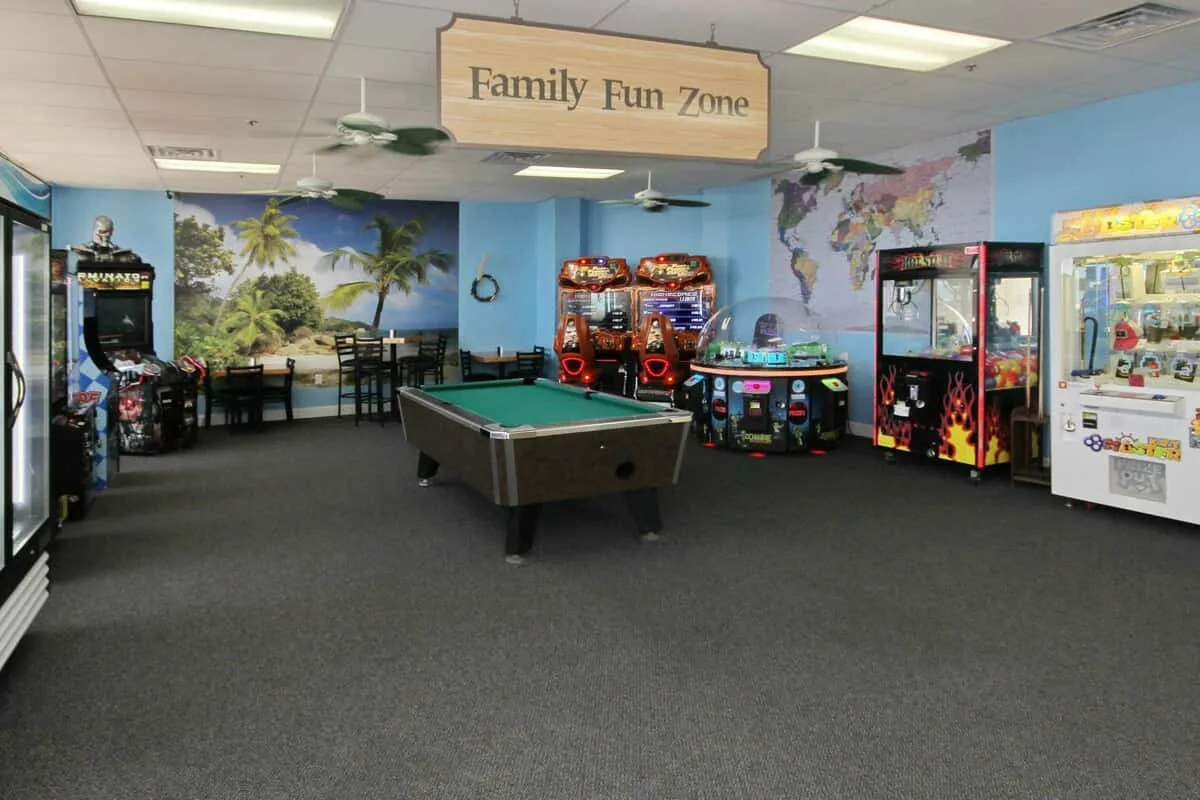 Una sala de juegos interior cuenta con una mesa de billar y varias máquinas recreativas.