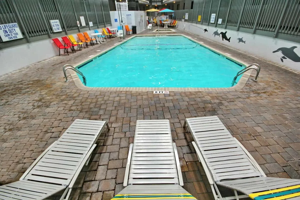 Una piscina cubierta está rodeada de una zona pavimentada y tumbonas.