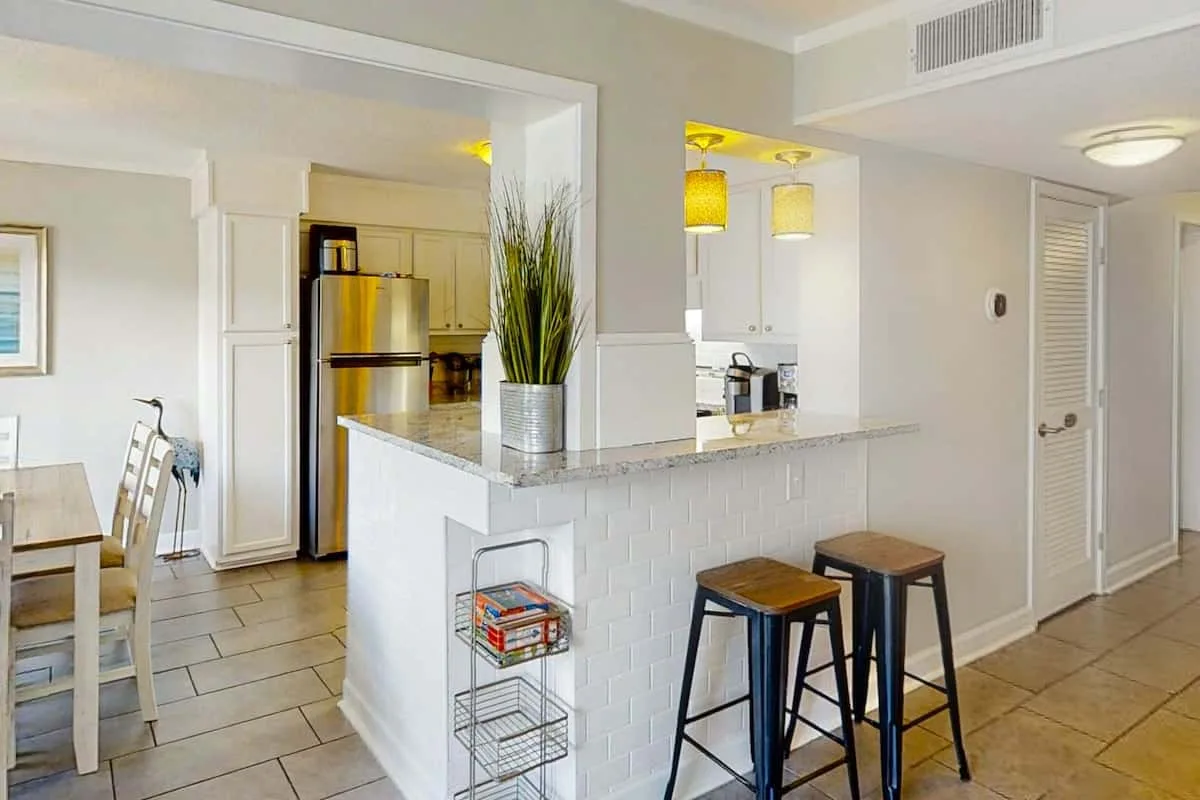 An open-plan kitchen and dining area with a breakfast counter and bar stools.