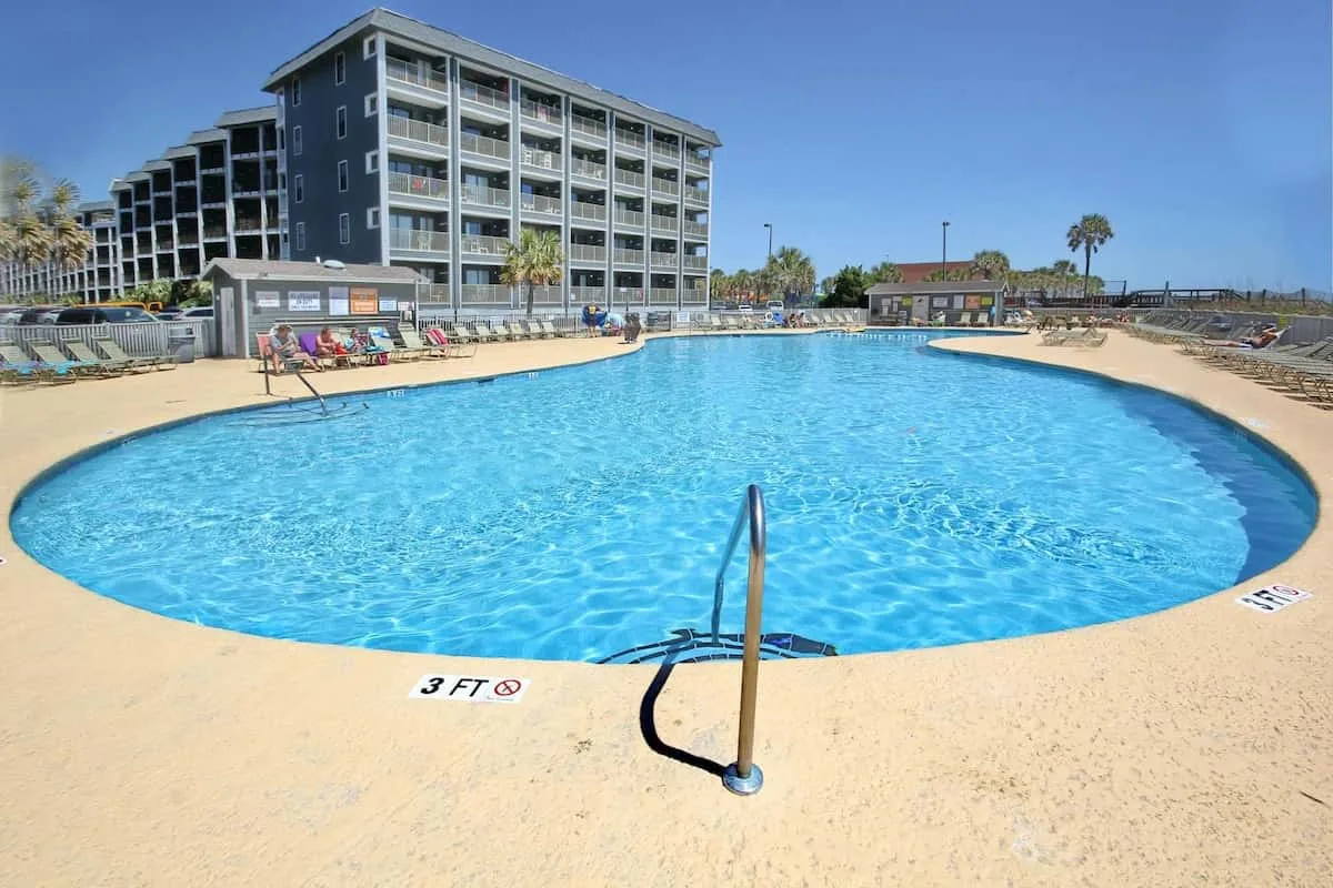 Una gran piscina al aire libre está junto a un edificio de varios pisos.