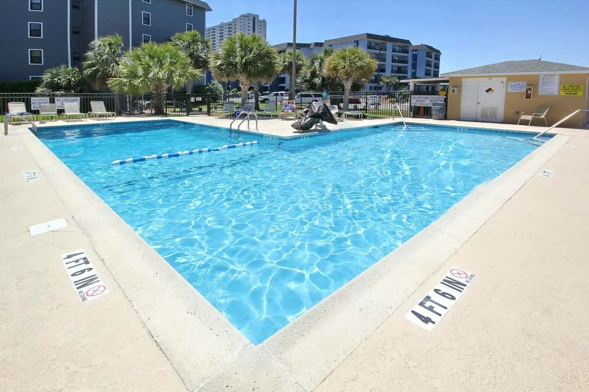 Una piscina al aire libre con una línea divisoria flotante y palmeras cerca.