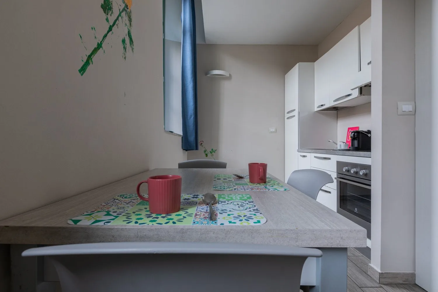 Una cocina compacta con una mesa y armarios blancos.