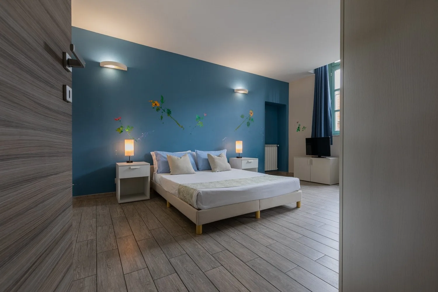 Un dormitorio con una cama, mesitas de noche y una pared azul.