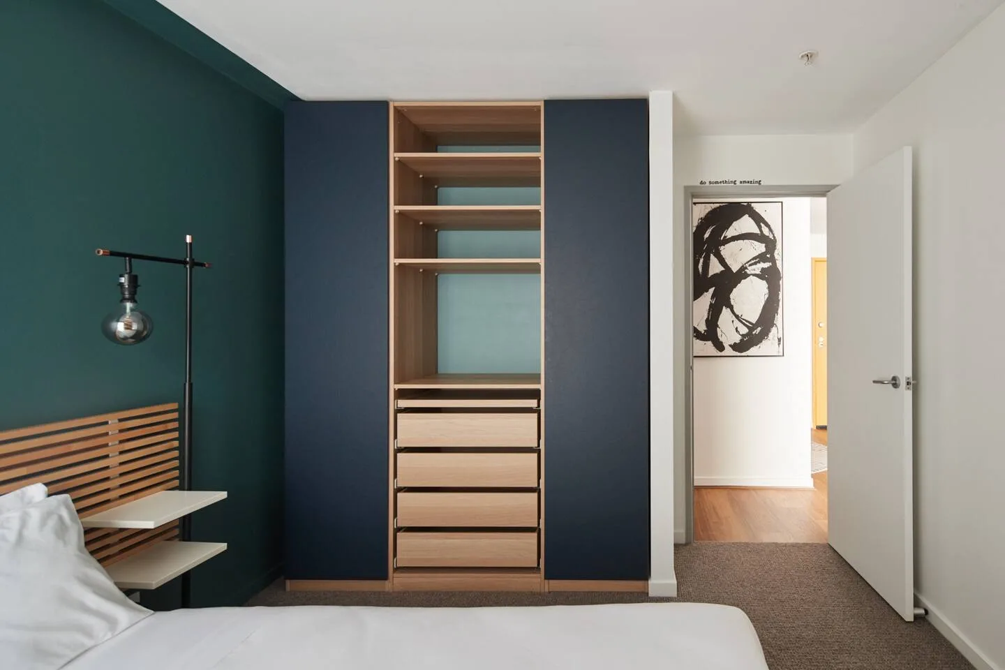 A bedroom with a built-in wardrobe, a bed, and a wall-mounted light.