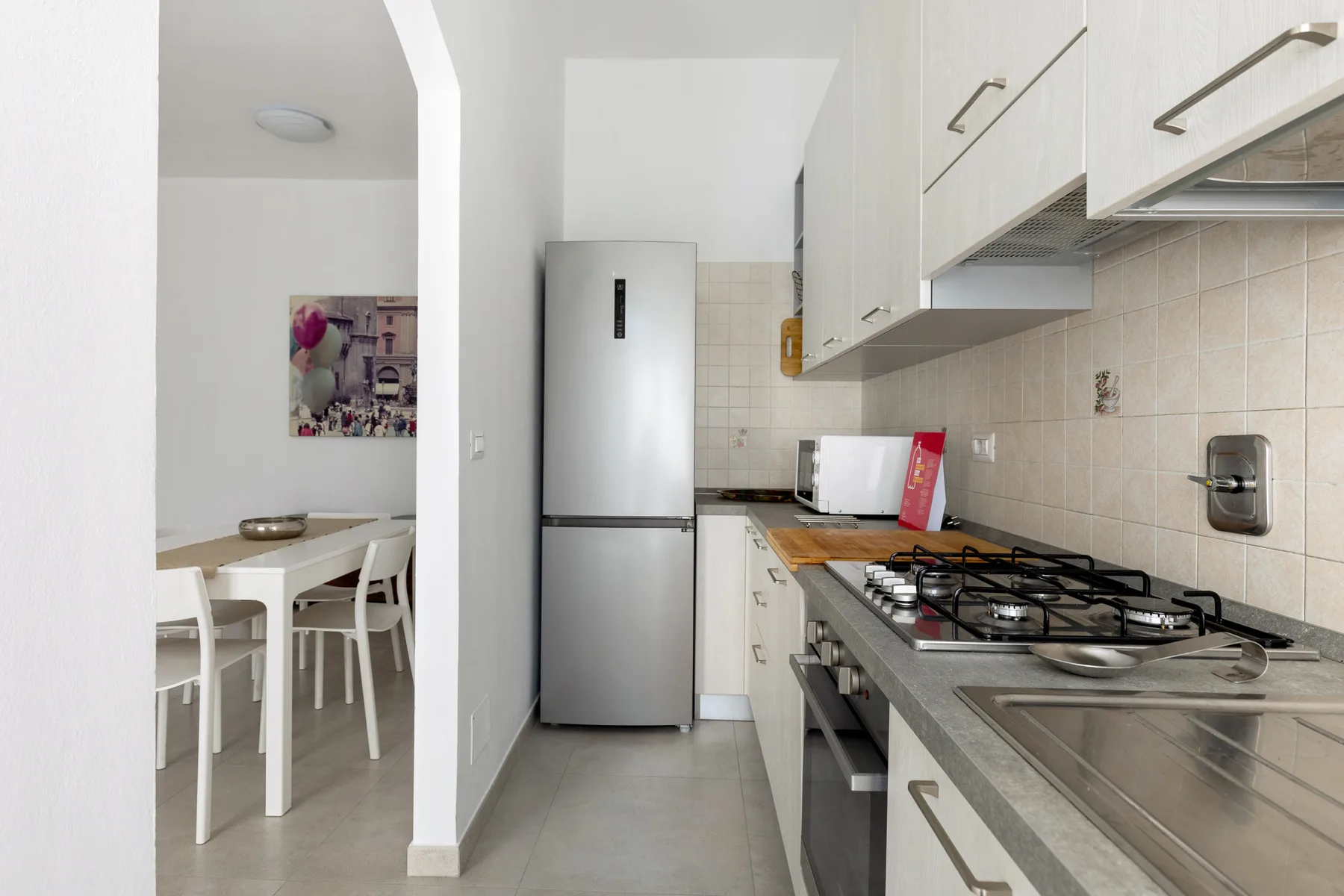 Una cocina estrecha con una cocina de gas, un fregadero y una mesa de comedor al fondo.