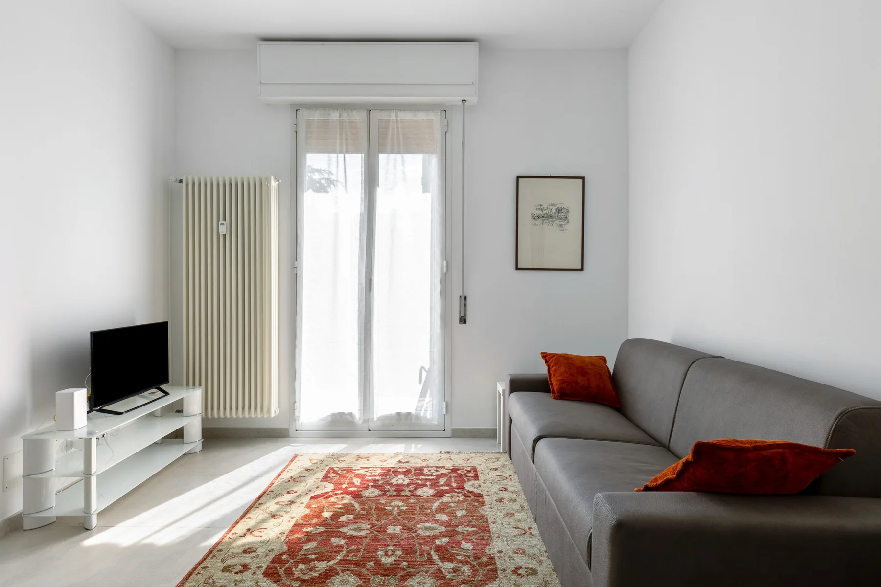 Una sala luminosa con asientos grises y una alfombra estampada.