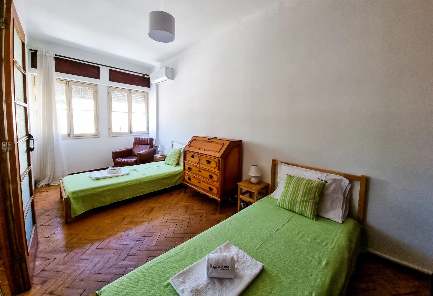 Un dormitorio con dos camas, ropa de cama verde y una cómoda de madera.