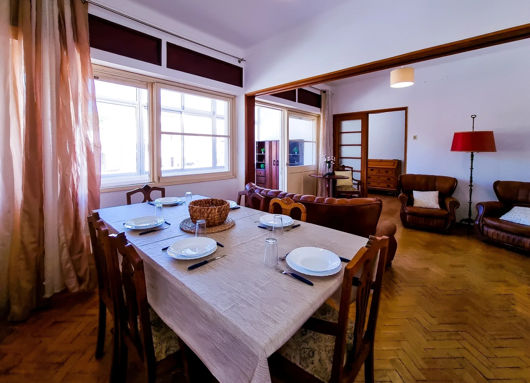Comedor con la mesa puesta junto a una zona de estar.