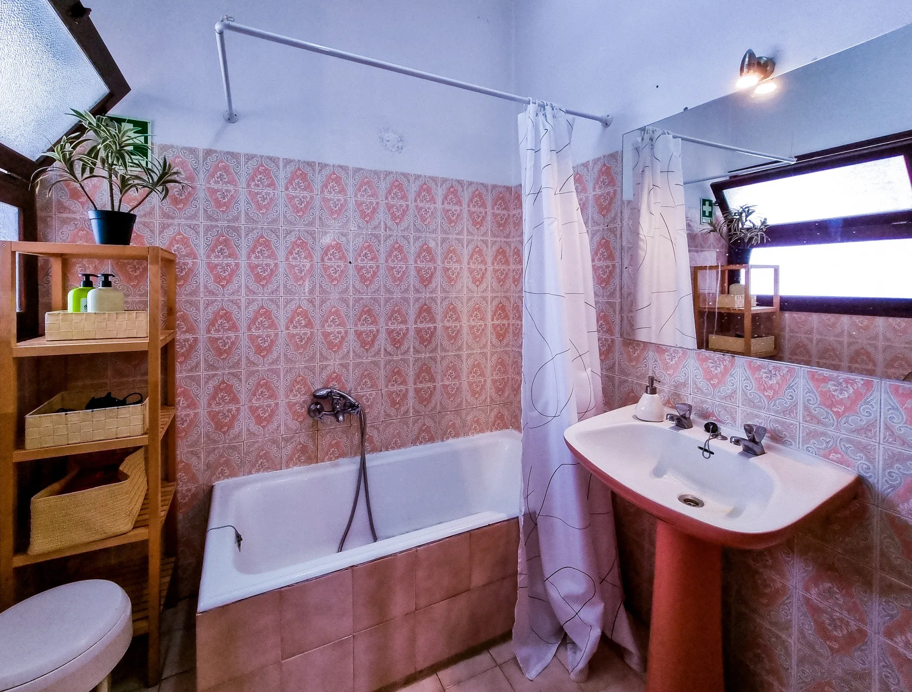 Un baño con bañera, lavabo y paredes de azulejos estampados.