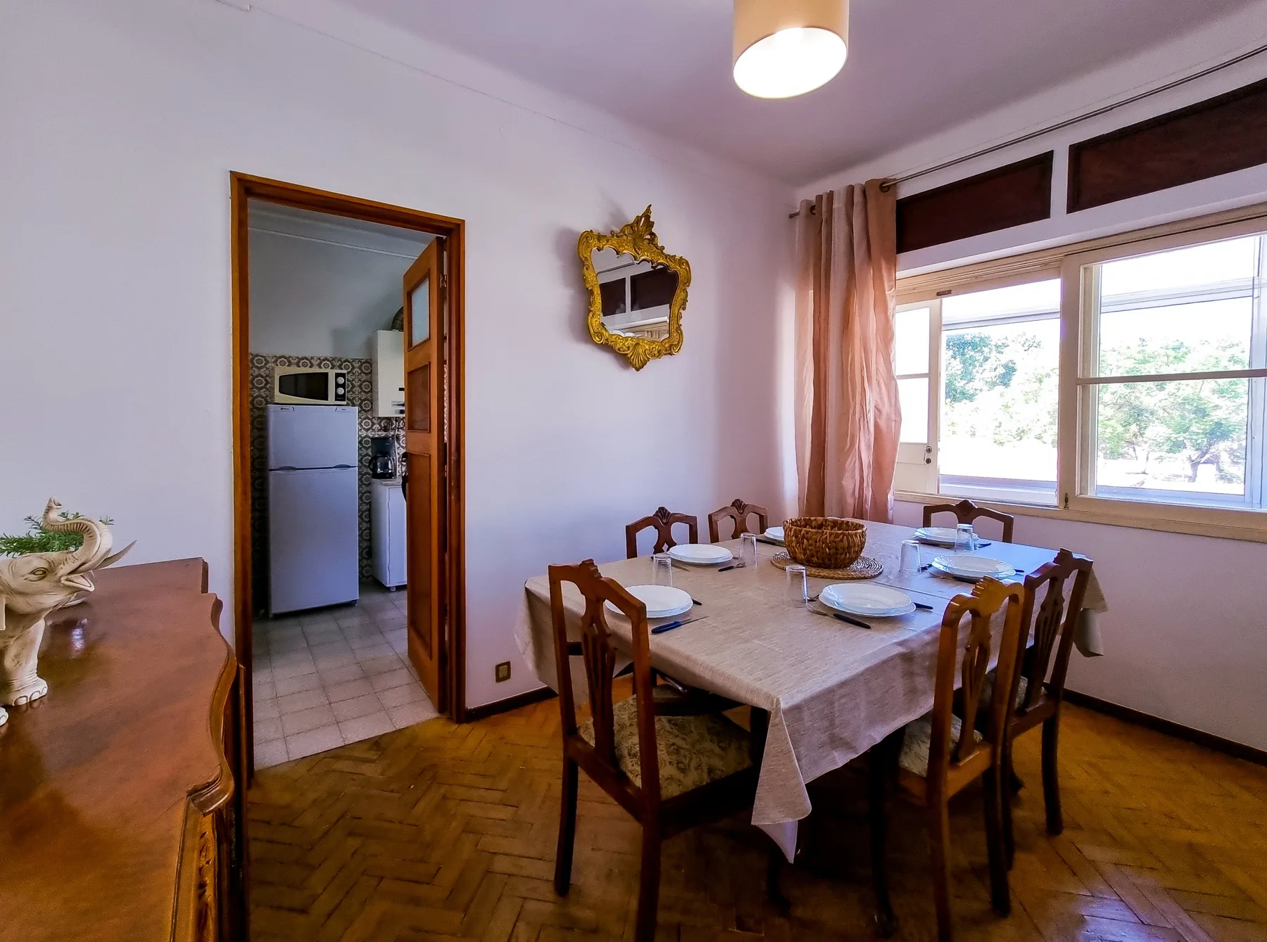 Comedor con una mesa de madera y sillas junto a grandes ventanas.