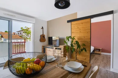 A bright living and dining area with a wooden table and sliding glass doors.