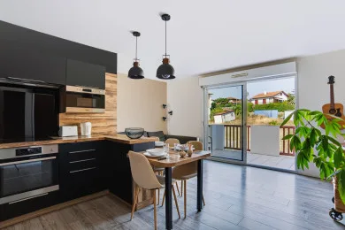 A modern kitchen and dining area opens onto a patio through large glass doors.