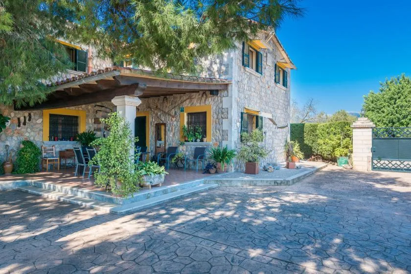 Stone house exterior with a shaded patio and paved courtyard.