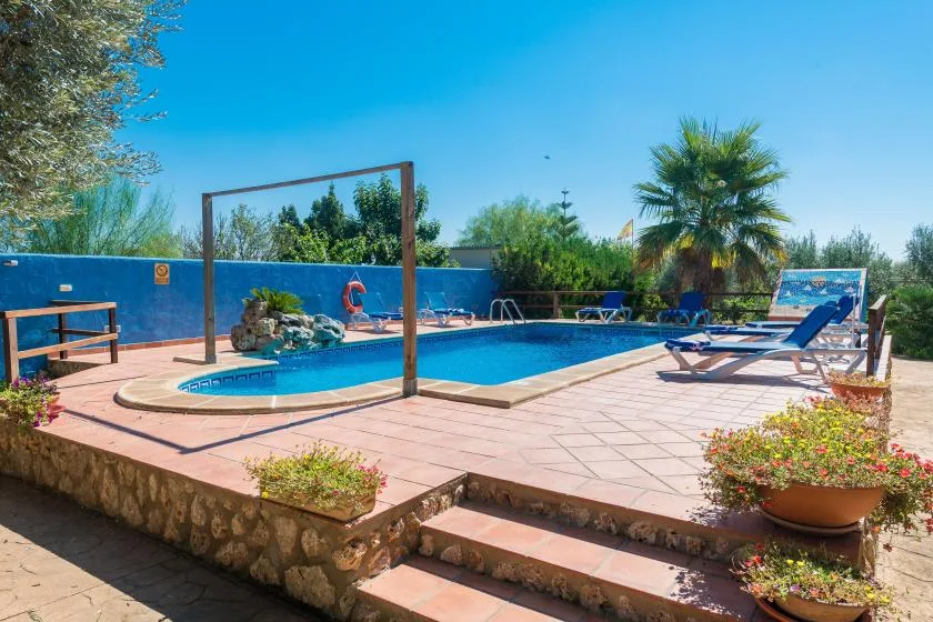 An outdoor swimming pool is surrounded by a paved patio and lounge seating.
