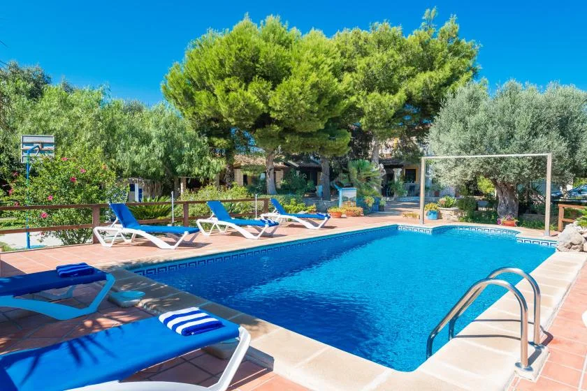 An outdoor swimming pool is surrounded by lounge chairs and greenery.