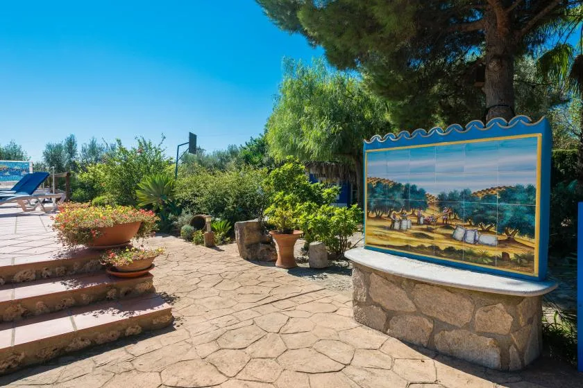 A stone-paved garden patio with planted pots and a colorful tiled display.