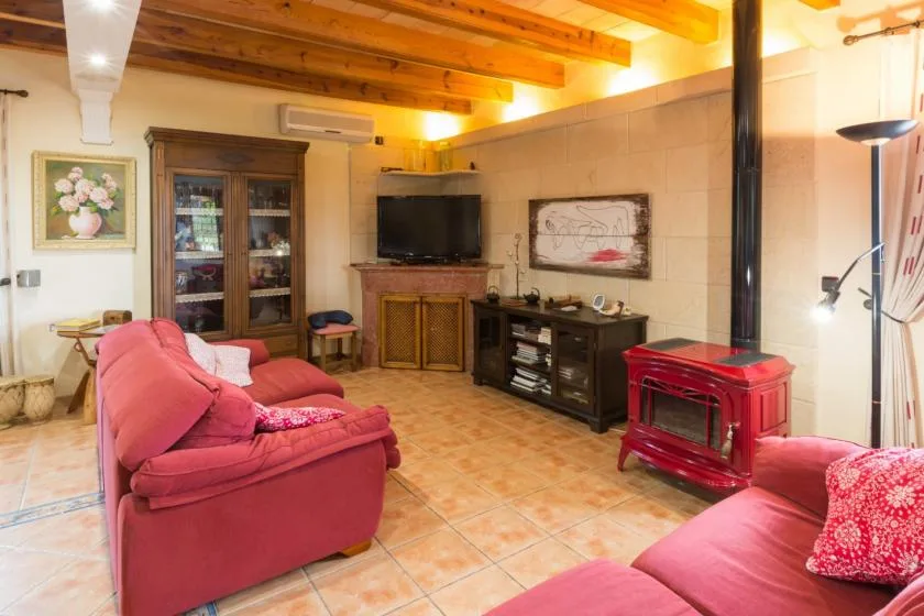 A living room with red seating, a television, and a red stove.