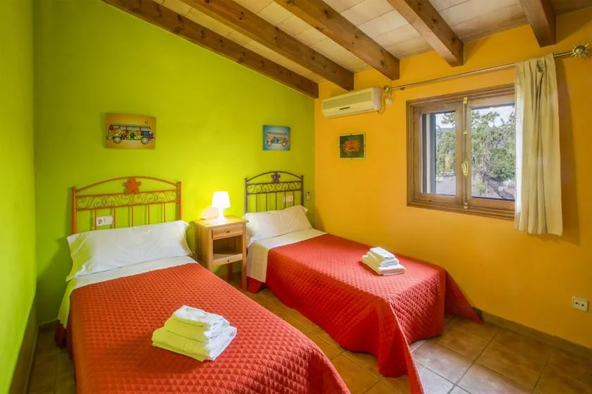 A twin bedroom with two beds, a bedside table, and a window.