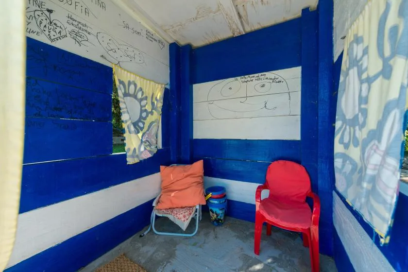 A small blue room with two seats and patterned curtains.