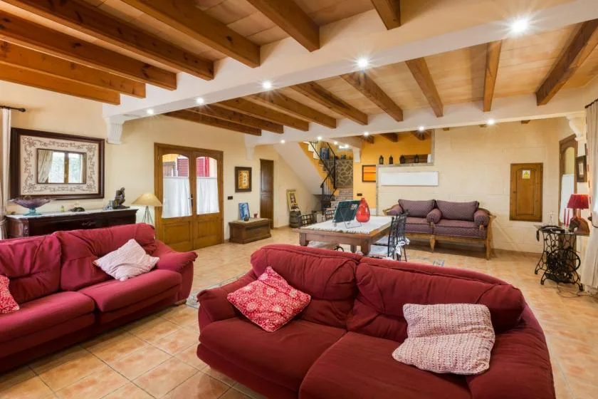 A living room with red seating and exposed wooden ceiling beams.