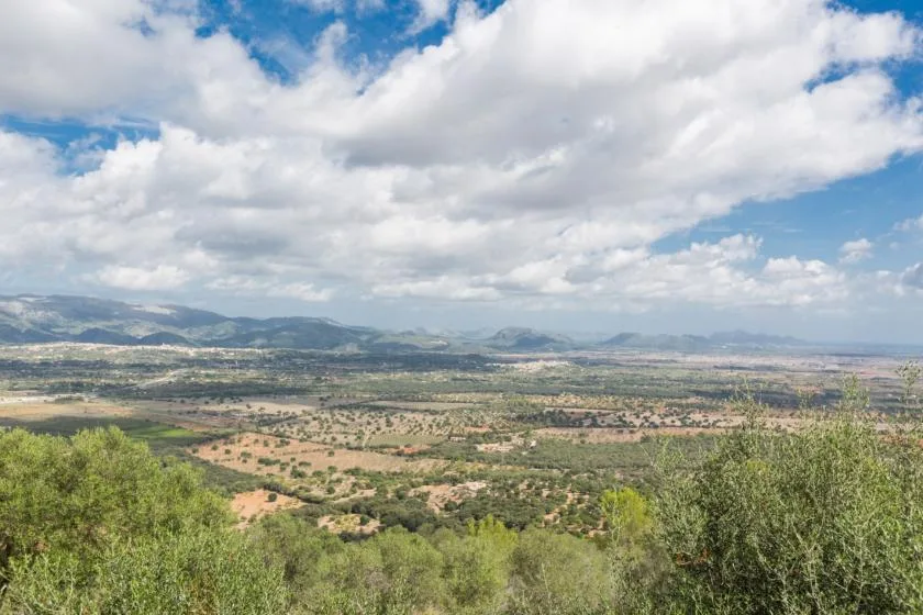 A broad valley landscape stretches beneath a cloudy sky.