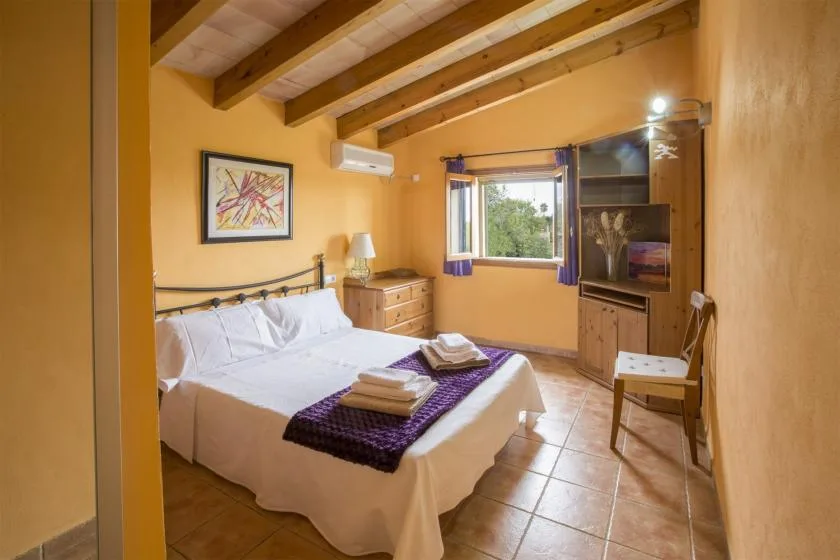 A bedroom with a bed, folded towels, and a window.