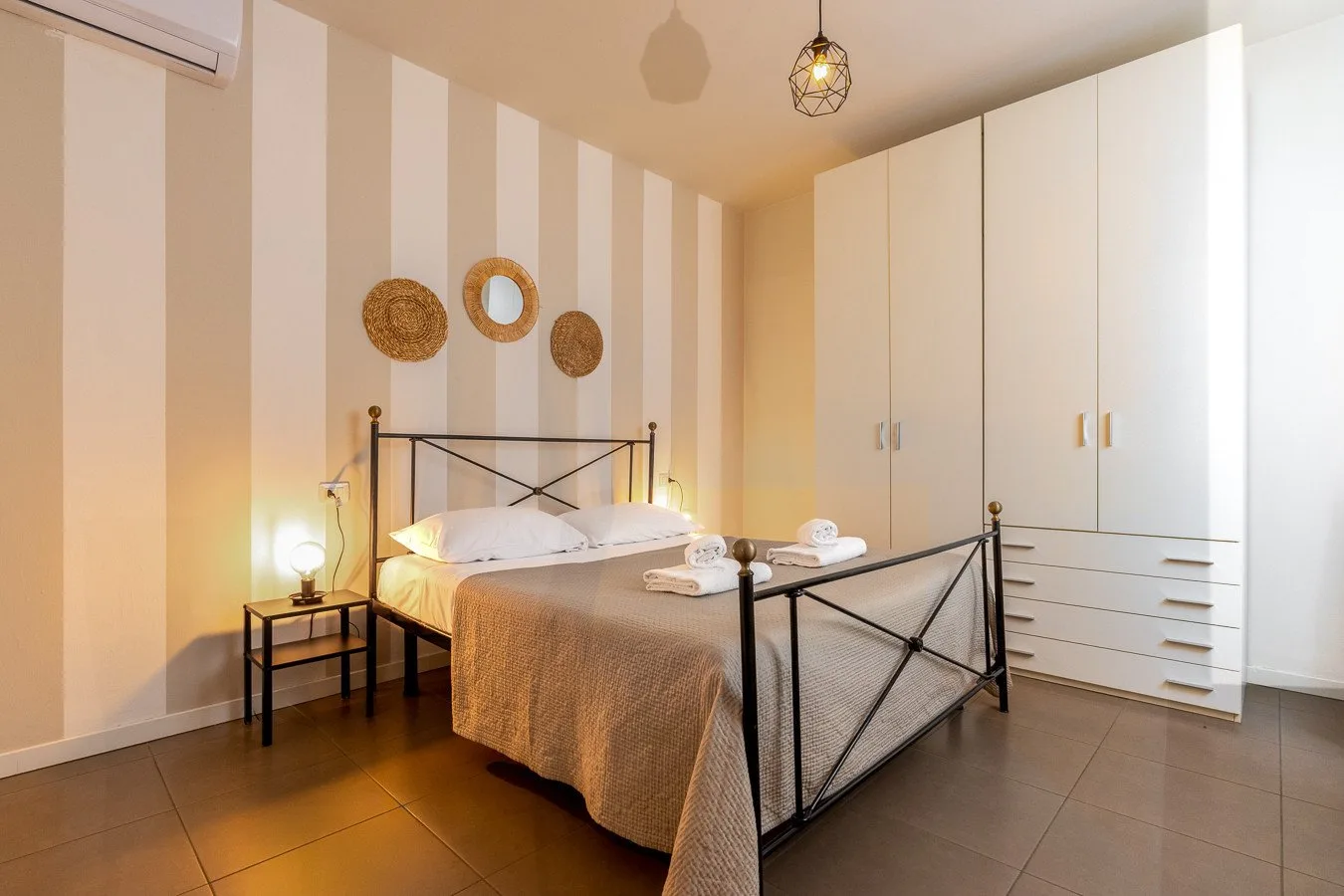 Dormitorio con una cama, una mesita de noche y un armario blanco alto.