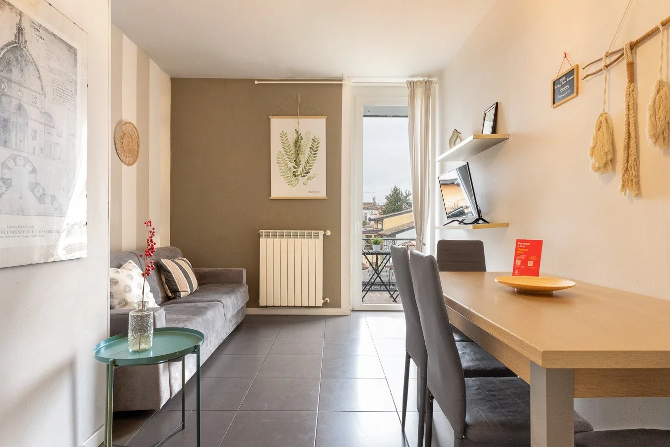 Una luminosa sala de estar y comedor con sofá, mesa y puertas al balcón.