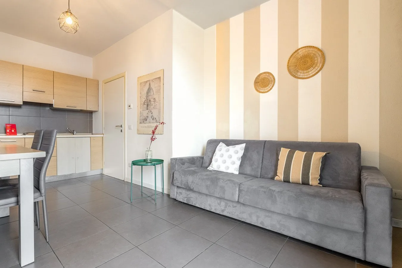 Una sala de estar con un sofá gris junto a una cocina abierta.