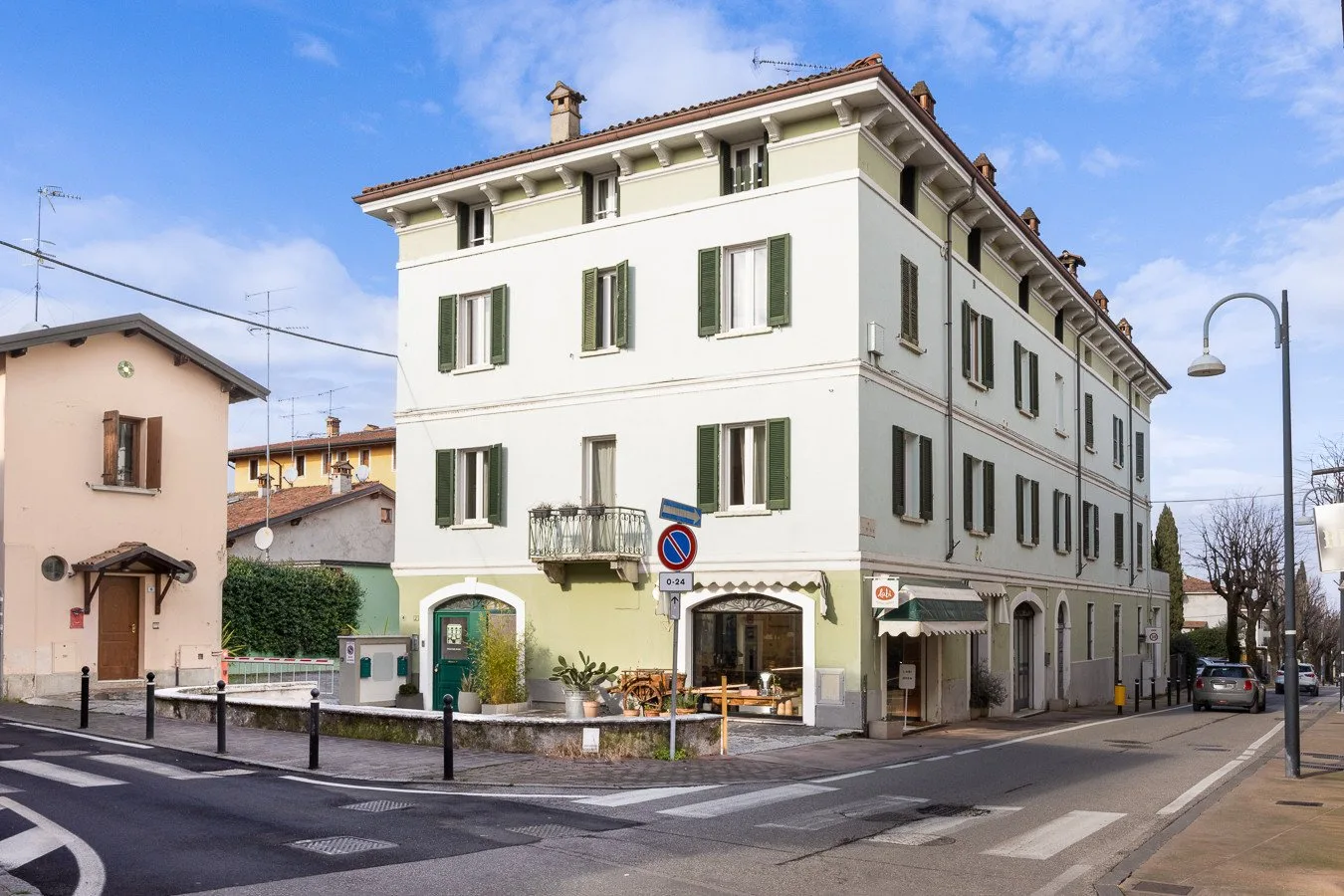 Un edificio claro de varias plantas está en una esquina junto a un paso peatonal.
