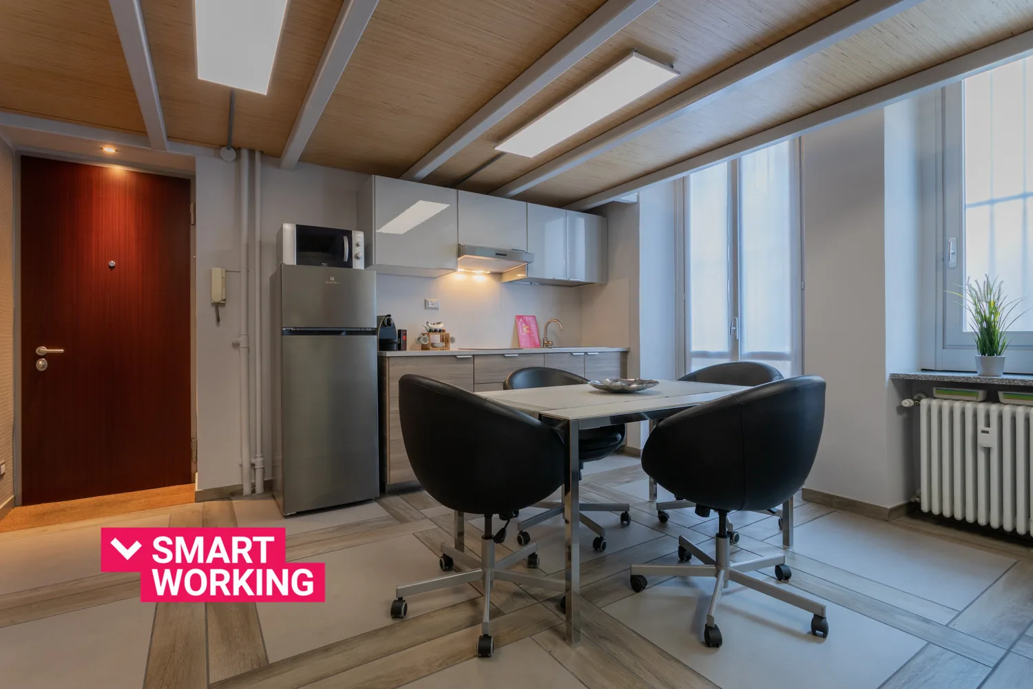 Una cocina y comedor con una mesa, asientos y grandes ventanas.