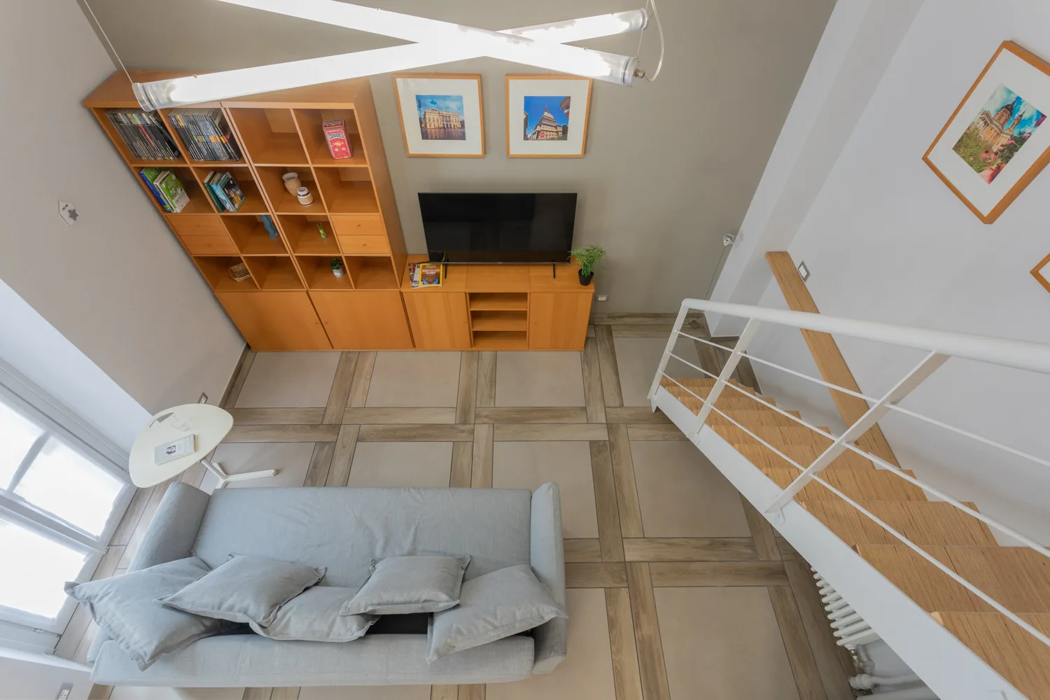 Una sala de estar con asientos grises, estanterías de madera y un televisor.