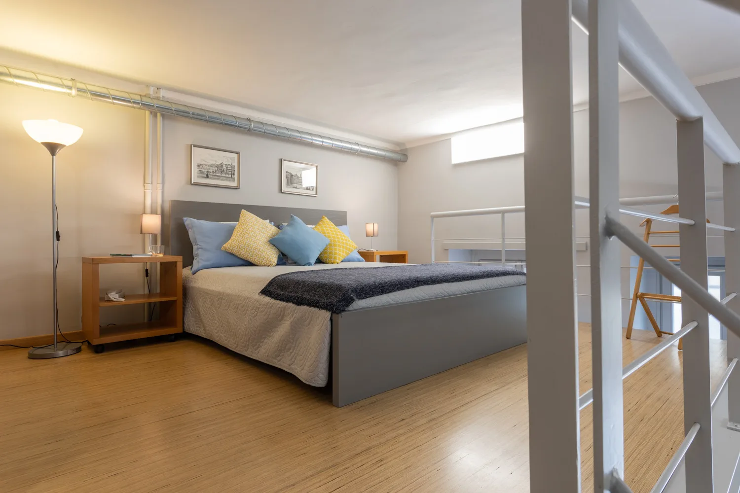Un dormitorio con una cama, cojines de colores y una lámpara de pie.