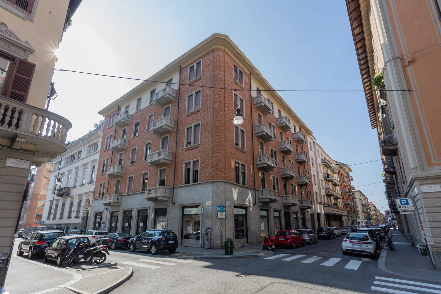 Una esquina urbana flanqueada por edificios de apartamentos y coches estacionados.