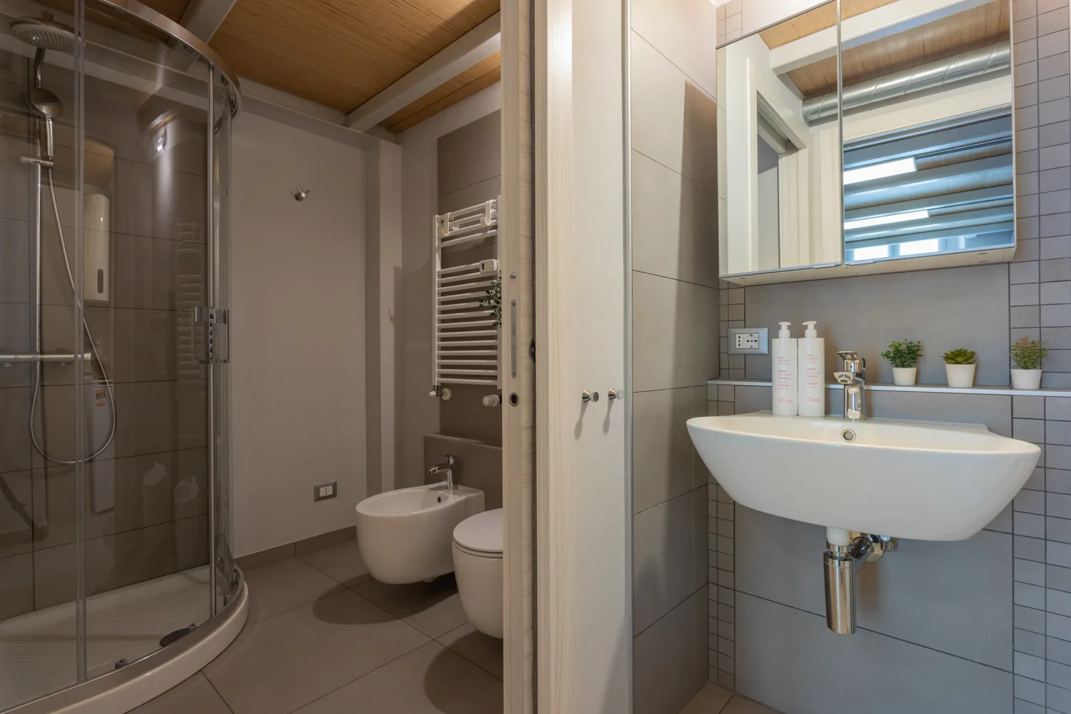 Un baño con ducha de cristal, inodoro y lavabo suspendido.