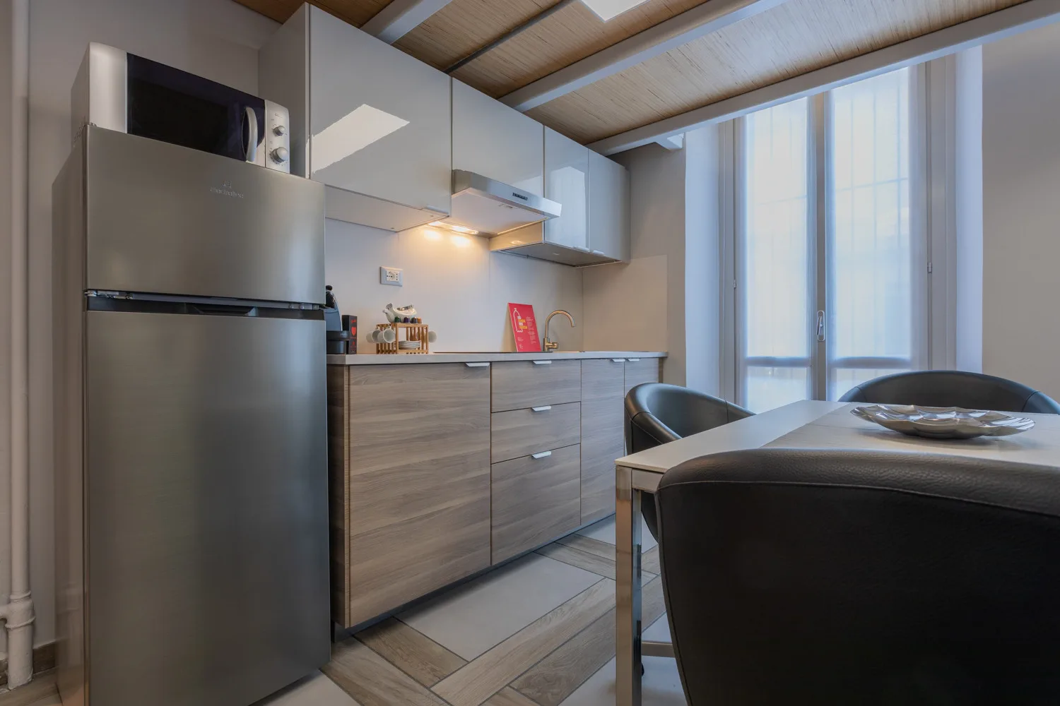 Una cocina moderna con una mesa de comedor junto a ventanas altas.