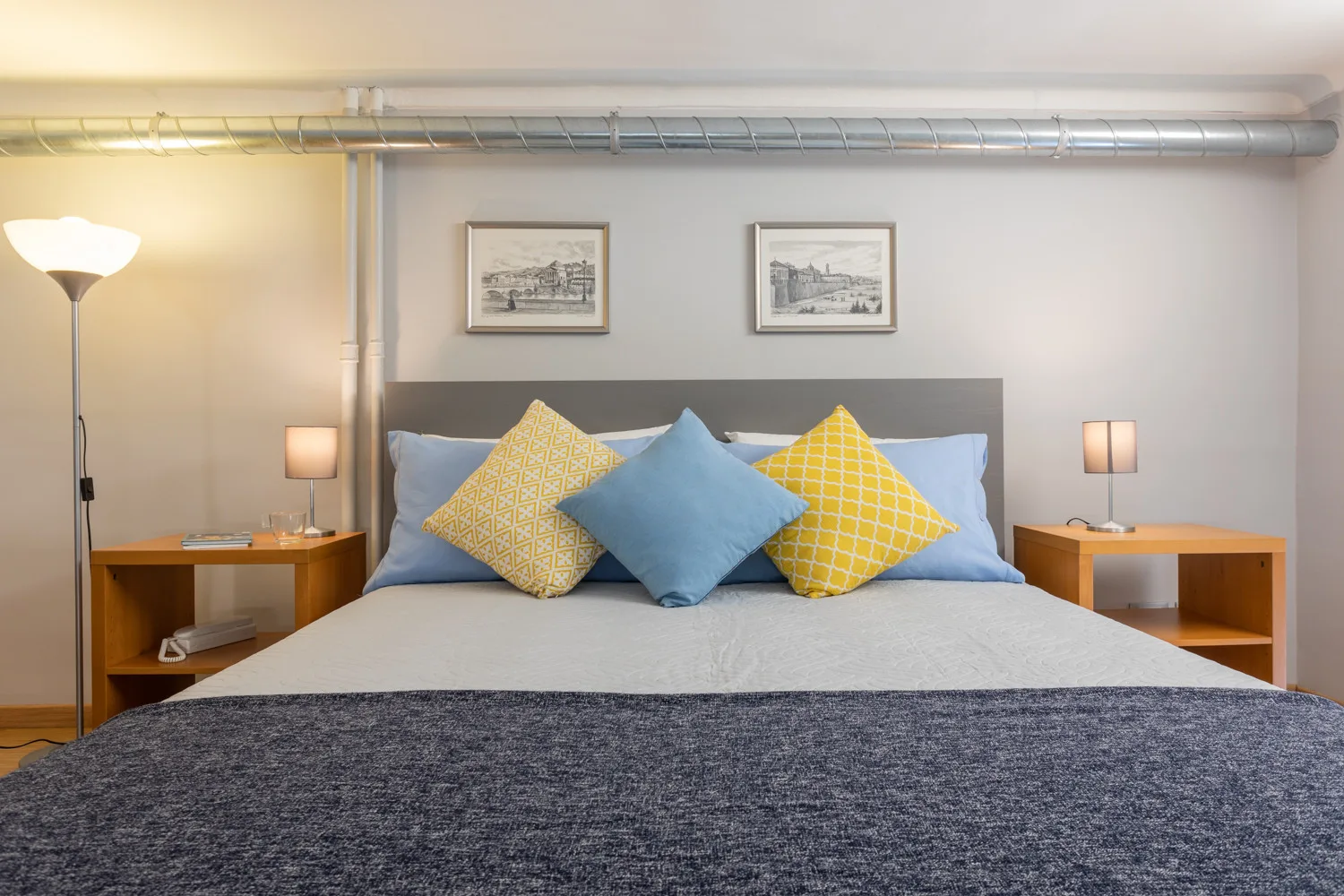 Un dormitorio con una cama bien tendida y cojines de colores.