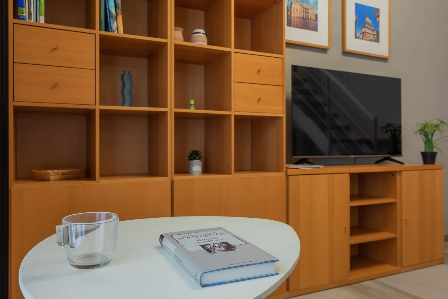 Una sala de estar con estanterías de madera, un televisor y un libro sobre la mesa.