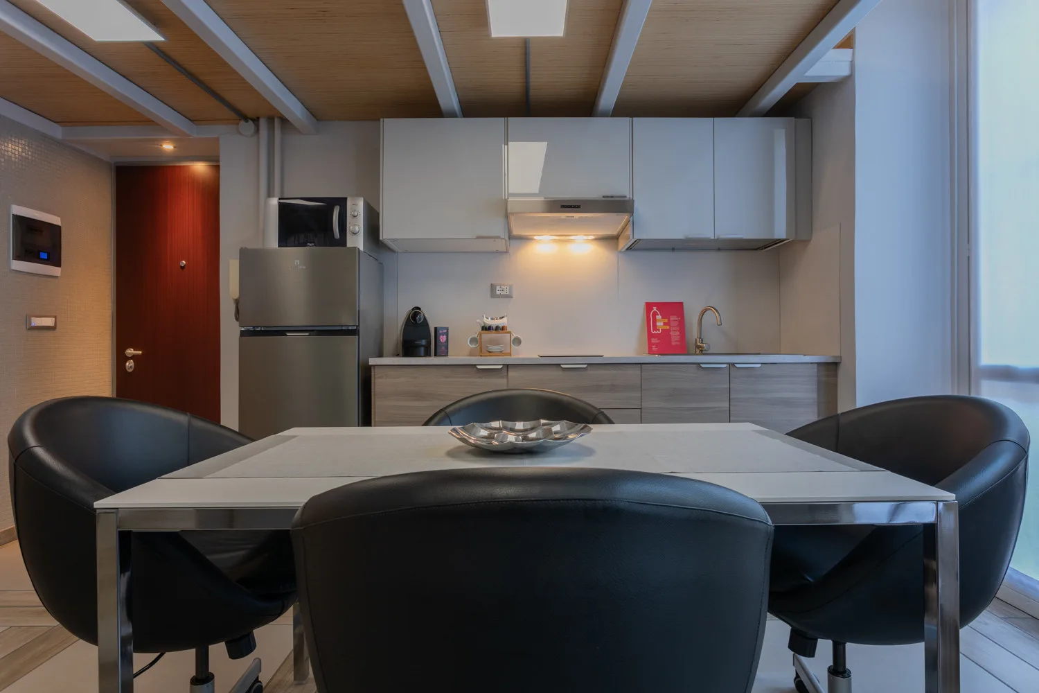 Un comedor con mesa y asientos frente a una cocina compacta.