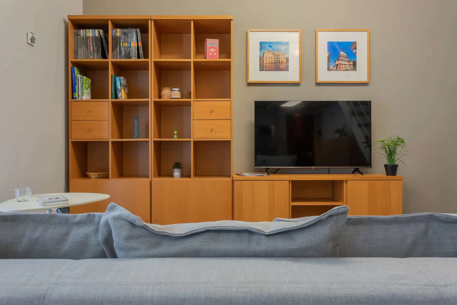 Una sala de estar con televisor, estantería de madera y asientos.