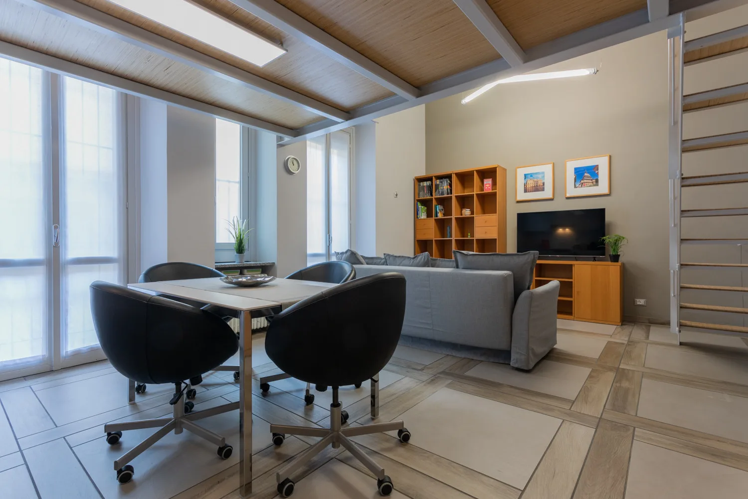Una sala luminosa tiene una mesa de comedor, asientos y un televisor.