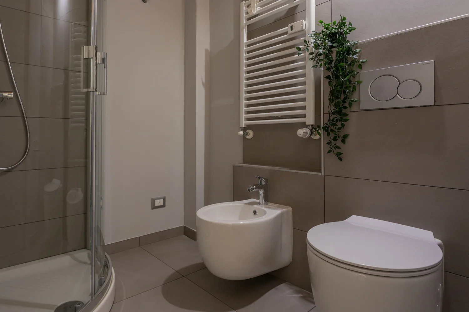 Un baño moderno con ducha, lavabo suspendido e inodoro.