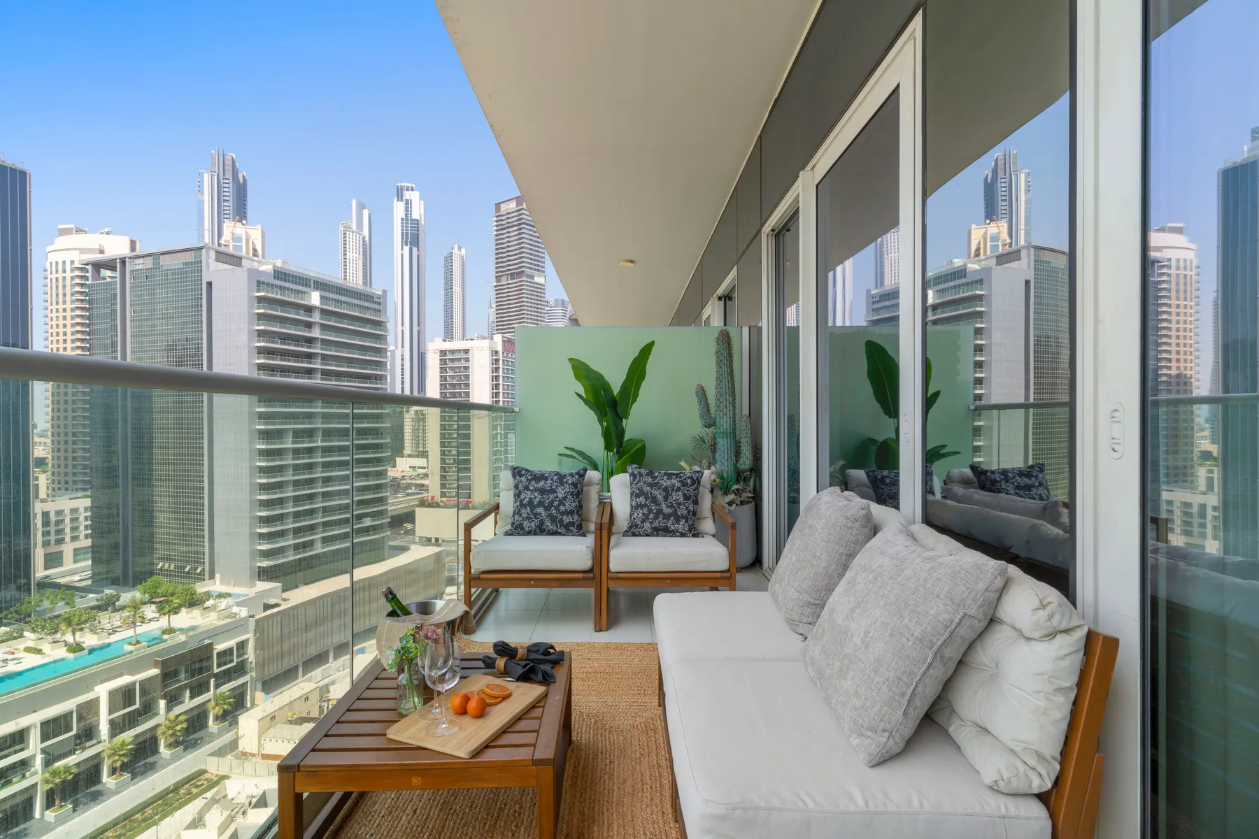 Una zona de estar en el balcón, con cojines, da a un horizonte urbano.