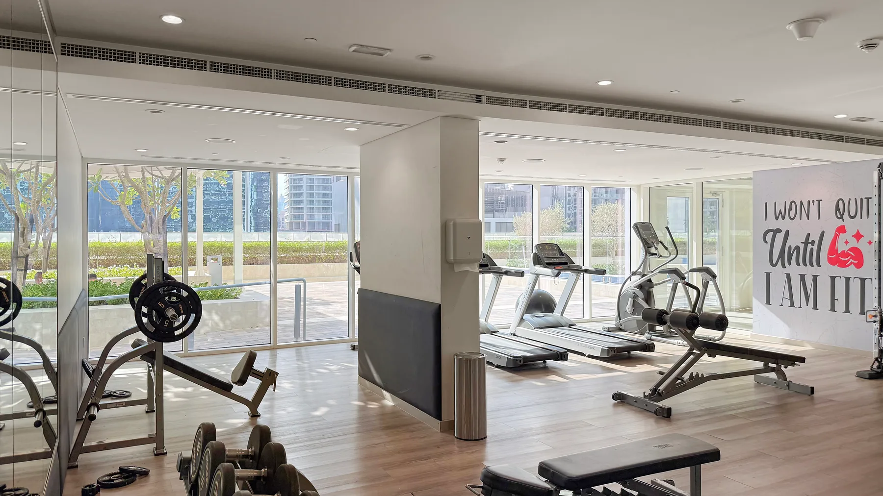 Un gimnasio luminoso con cintas de correr, bicicletas estáticas y pesas.