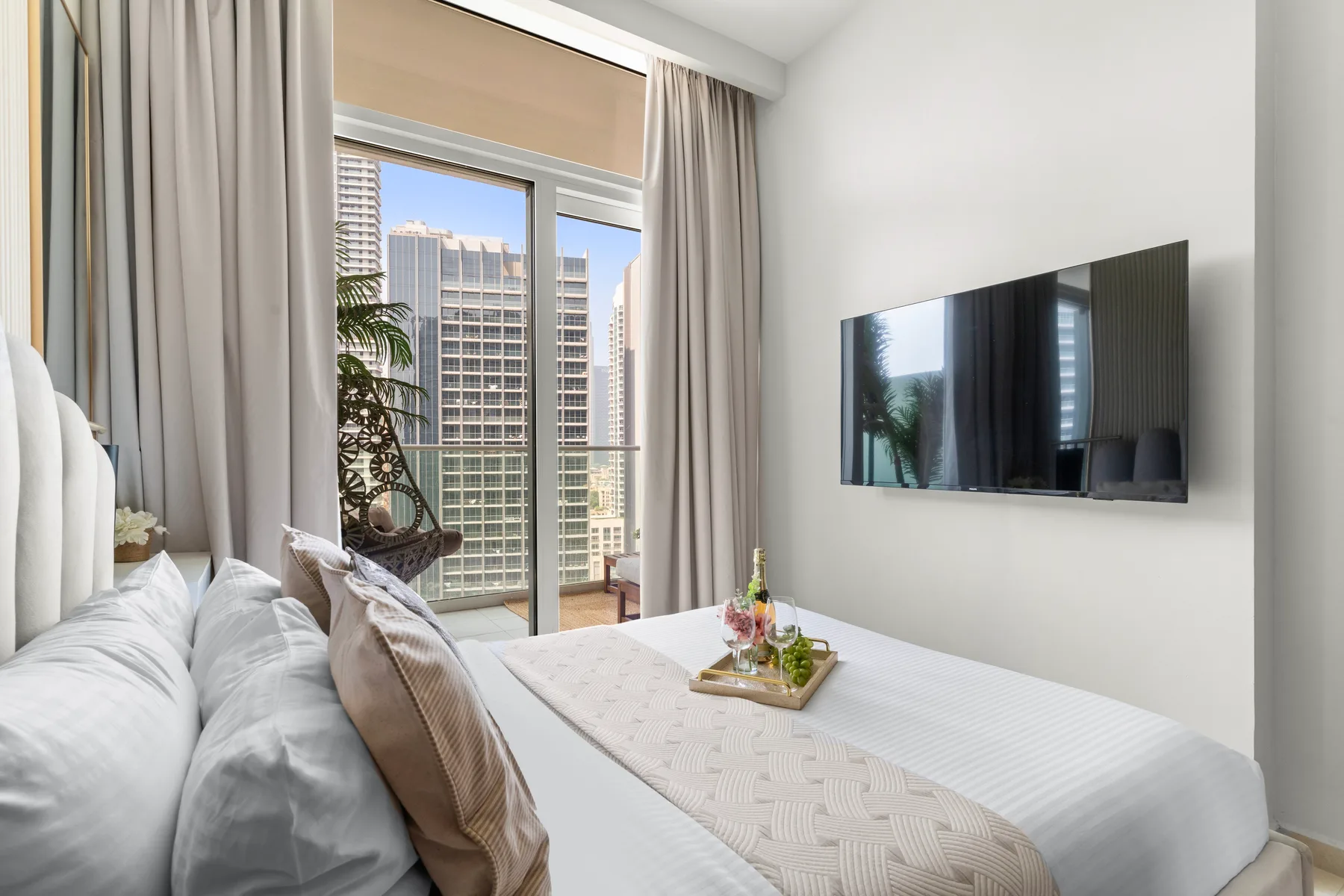 Un dormitorio con una cama bien tendida y un televisor montado en la pared.
