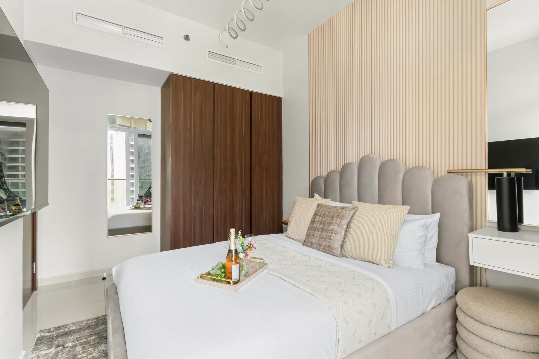 Un dormitorio con una cama tendida, un cabecero tapizado y una mesa de noche.