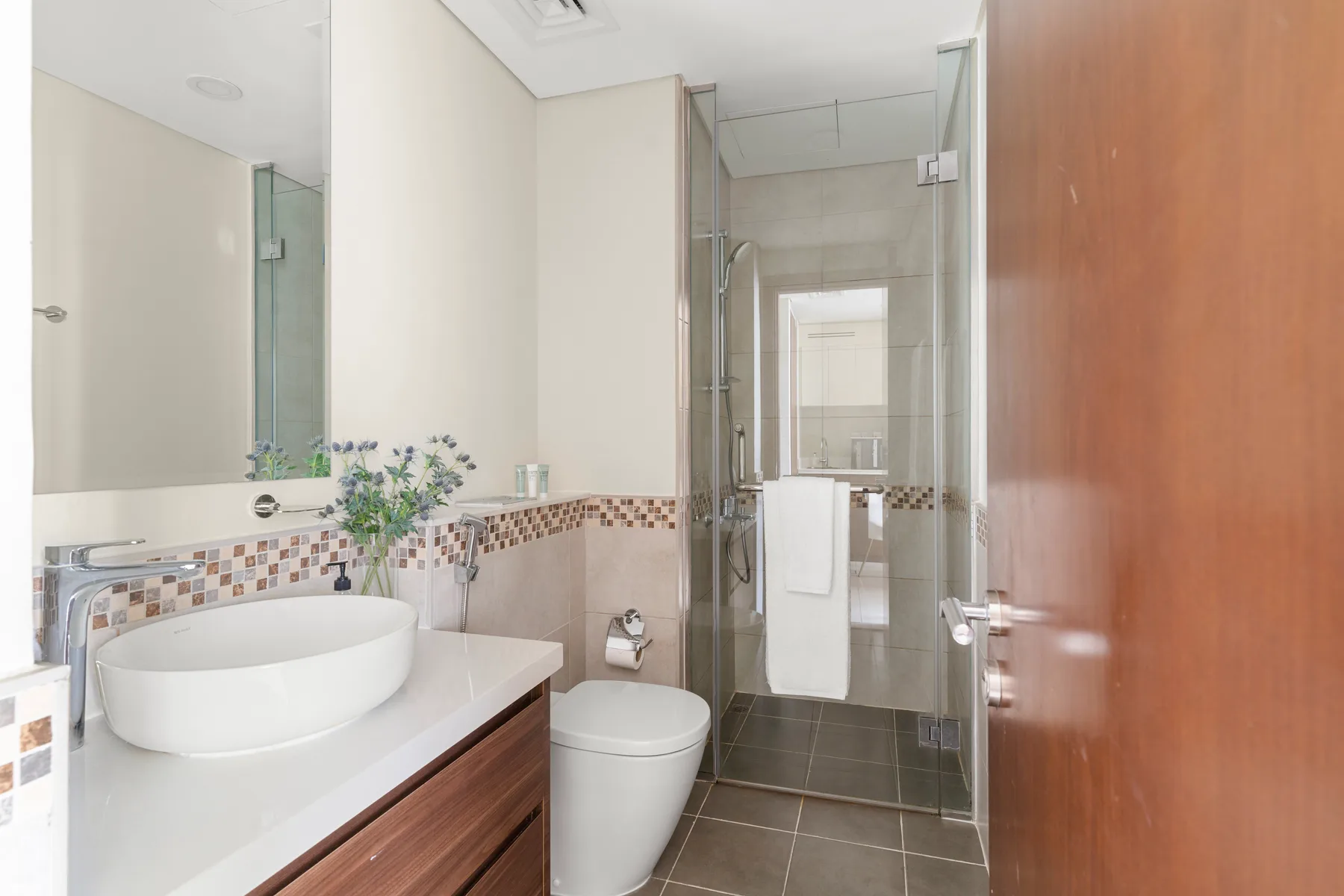 Un baño con lavabo sobre encimera, inodoro y ducha de vidrio.